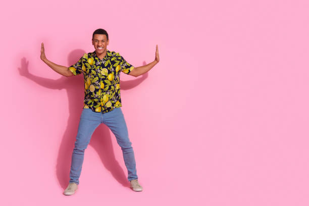istock Full length photo of handsome young guy push side wall empty space dressed stylish tropical print garment isolated on pink color background 2172567294
