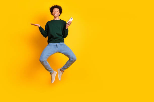 istock Full size photo of nice young man jump hold phone empty space wear pullover isolated on yellow color background 2172569302