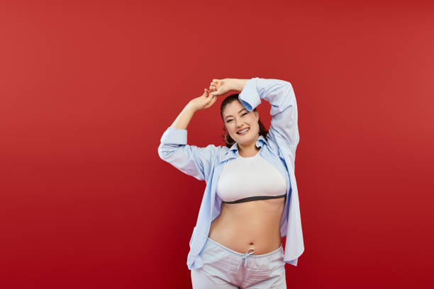 istock Celebrating body positivity, a joyful young woman strikes a playful pose in a red studio 2172574521