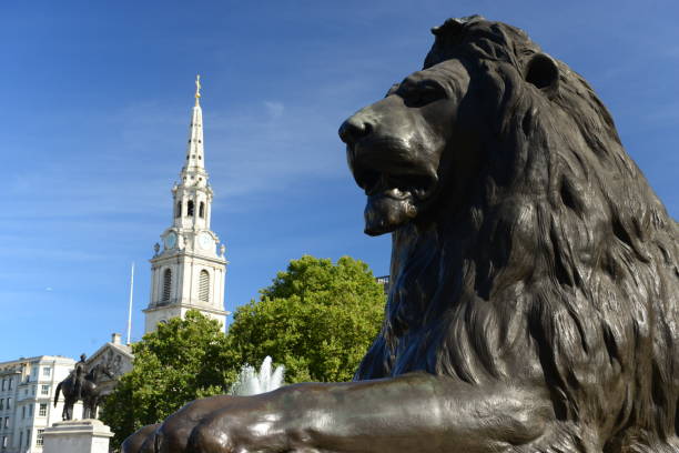 Bronze lion on a plinth and church spire of the square.