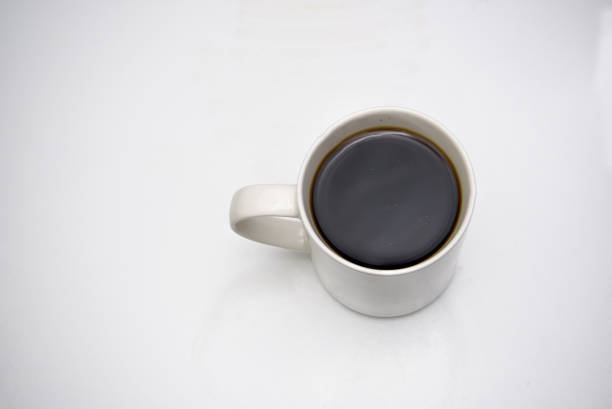 Unsweetened black coffee in a cup on a plain background. Photo taken from top