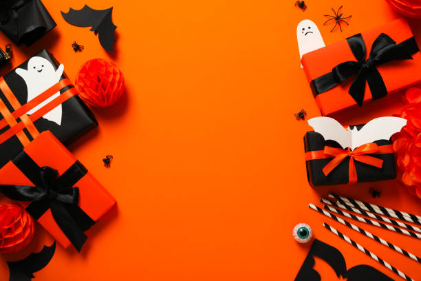istock Gift boxes, paper ghosts and bat on orange background, space for text 2172576874