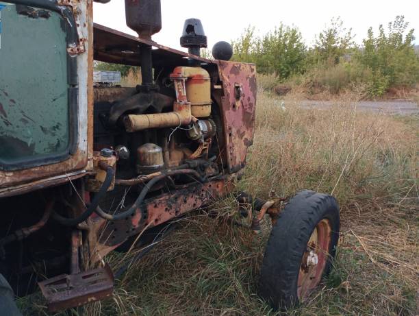 The front and engine compartment of an old rusty destroyed tractor in the open air. Old agricultural machinery.