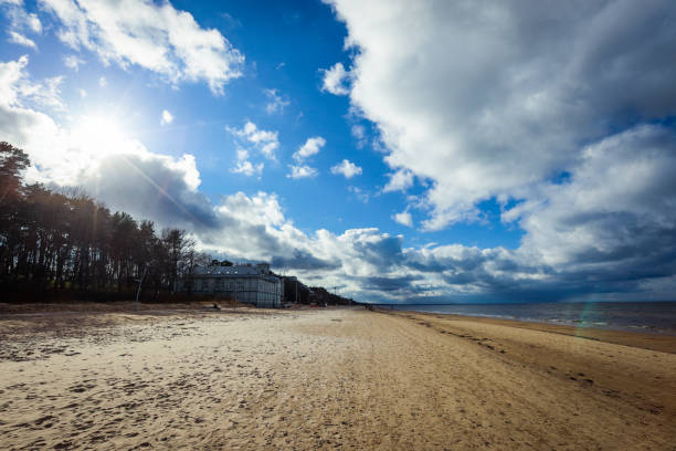The beach in Jurmala showcases soft sand and tranquil waters under a vast sky filled with clouds. This peaceful setting invites relaxation and reflection during the afternoon.
