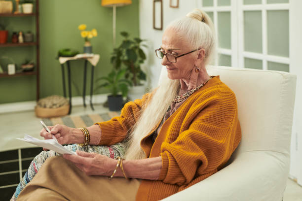 istock Elderly Woman Writing While Sitting in Comfortable Chair 2172580912