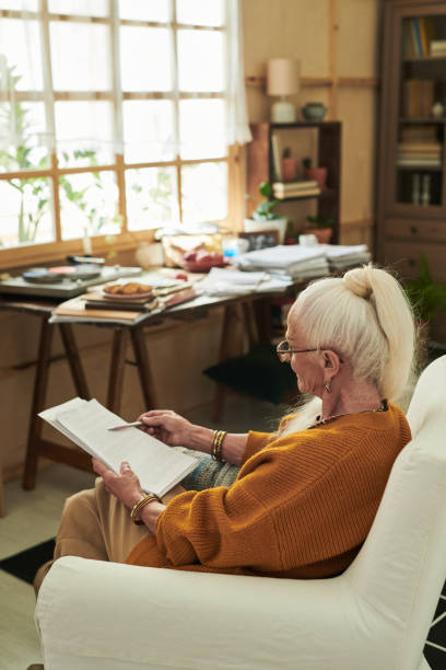 istock Senior Woman Sitting Indoors Reading Book Peacefully 2172580914
