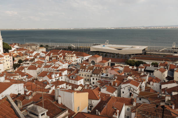 A stunning view of the Alfama district's red rooftops against he backdrop of the Tagus River, highlighting the charm and beauty of one of Lisbon's oldest neighborhoods.