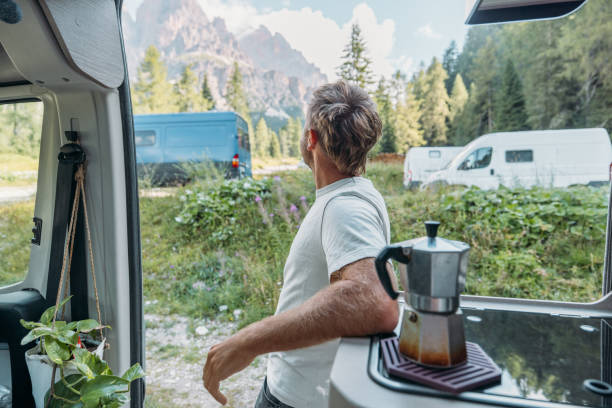 istock Man Relaxing Outside Campervan with Coffee Maker in Scenic Mountains 2172582874
