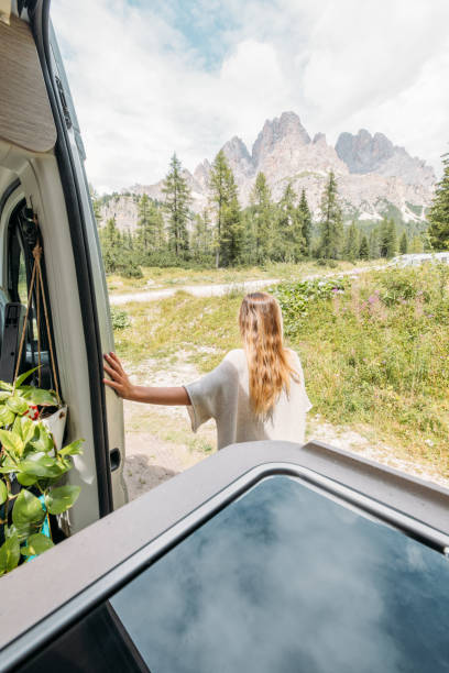 istock Woman Smiling Outside Campervan in Mountain Landscape 2172583202
