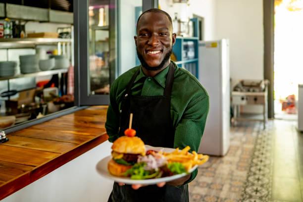 istock Smiling Chef Holding Burger and Fries in Restaurant Kitchen 2172584800
