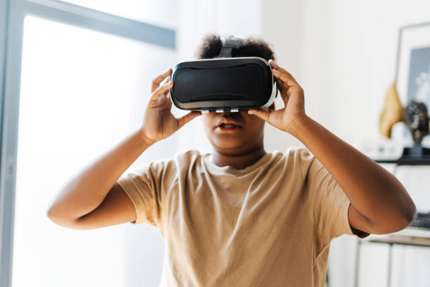 istock Amazed African American boy using VR headset while playing at futuristic game at home 2172585470