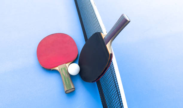 istock two ping-pong rackets and a ball on a green table. Close-up, ping-pong net. 2172587248