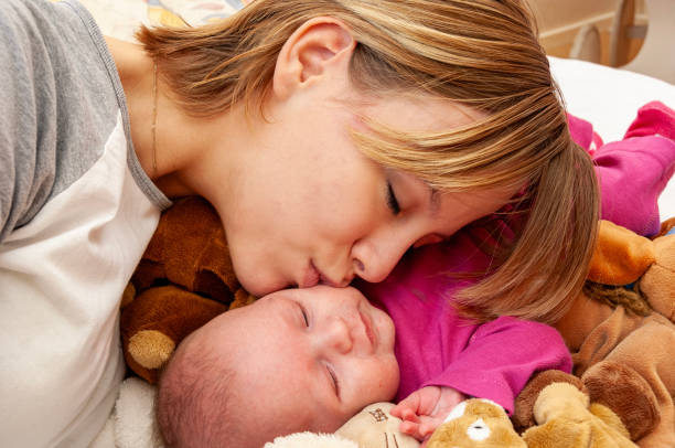 Close-up portrait of mother and baby. Eyes closed.