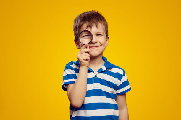 istock Curious happy kid examining environment with magnifying glass against yellow bright background 2172589978