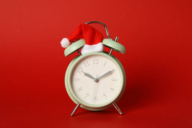 istock A clock in a Santa hat on a red background. 2172592729