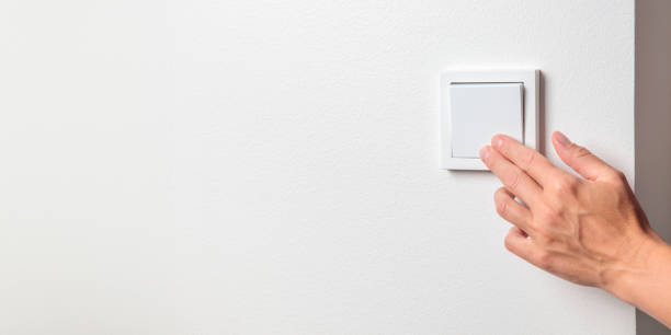 istock A woman's hand turning off a light switch on a white wall 2172593924