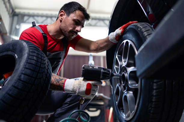 istock Mechanic removing wheels from vehicle with pneumatic impact wrench tool inside workshop. 2172594291