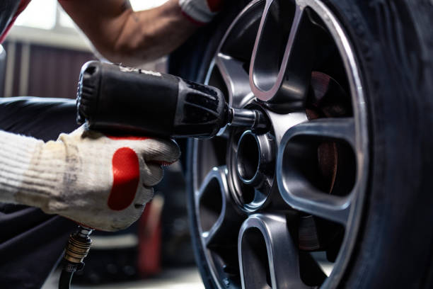 istock Removing wheels from vehicle with pneumatic impact wrench tool inside workshop. 2172594424
