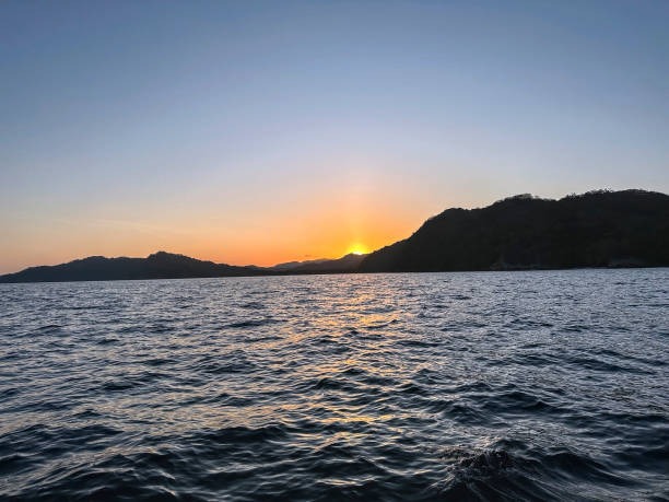 istock Sunset behind hills on island in the ocean 2172600933