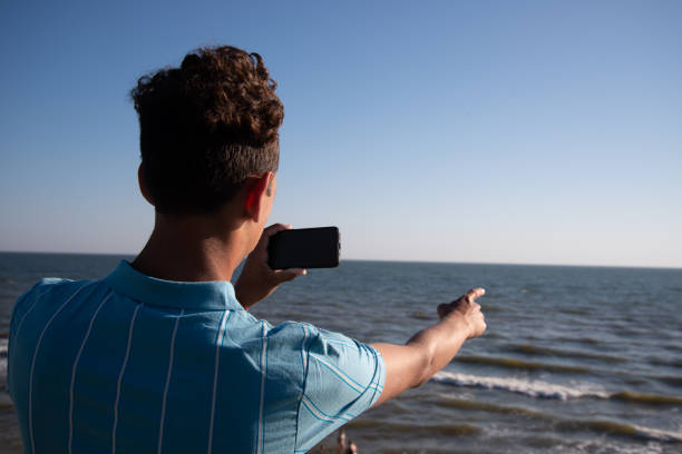 istock A young attractive guy is walking on the beach. 2172602044