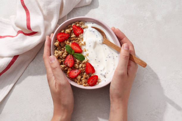 istock Bowl with yogurt and berries in hands and towel on light background 2172602239
