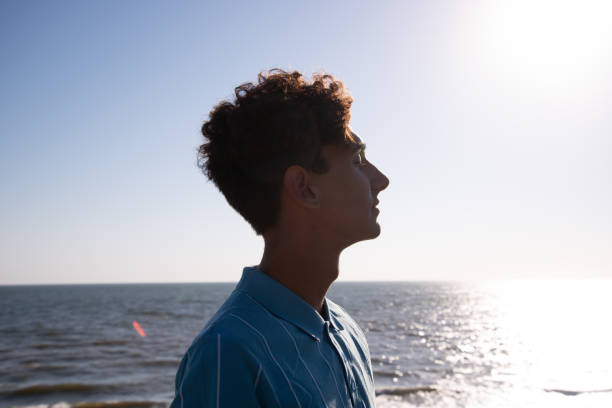 istock A young attractive guy is walking on the beach. 2172602634