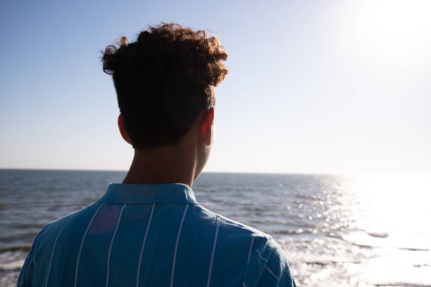 istock A young attractive guy is walking on the beach. 2172602693