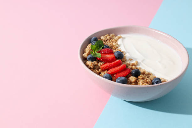istock Bowl with yogurt and berries on pink and blue background, space for text 2172603035