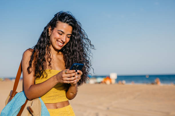 istock Young Woman Using Phone While Walking On The Beach In Barcelona In Spain 2172610988