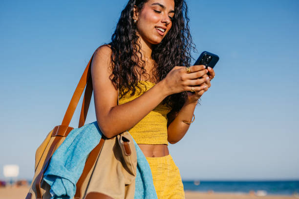 istock Young Woman Using Phone While Walking On The Beach In Barcelona In Spain 2172611741