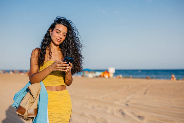 istock Young Woman Using Phone While Walking On The Beach In Barcelona In Spain 2172611774