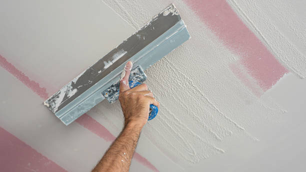 istock The worker make a plasterboard ceiling. He does sealing of joints with gypsum putty on plaster drywall ceiling. He is using special stainless steel taping knife. 2172617740