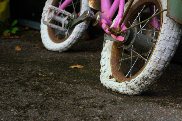 Old empty weathered children's bike tire on mossy asphalt
