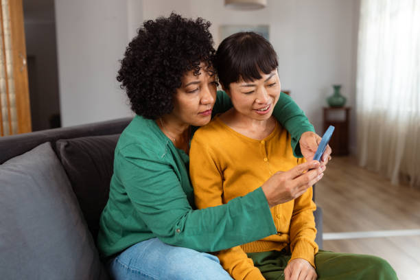 istock Diverse lesbian couple relaxing at home and using phone 2172620522