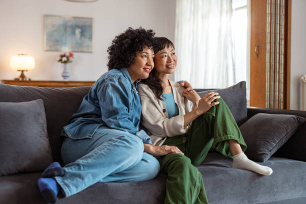 istock Diverse lesbian couple relaxing together on a comfortable sofa at home 2172620879