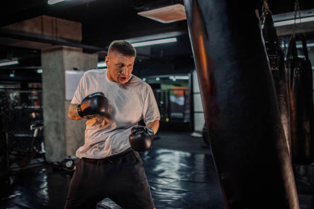 istock Man punching heavy bag intensely in boxing gym setting. 2172622324