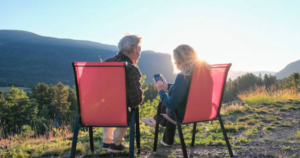 istock Mature couple relax in chairs and use mobile phone 2172634846