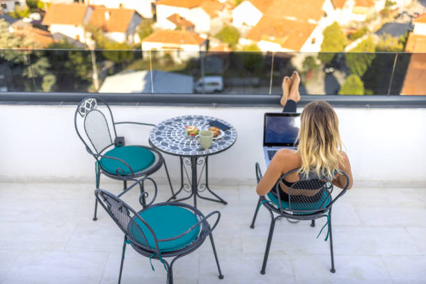 istock Woman sitting and working on laptop on balcony 2172643816