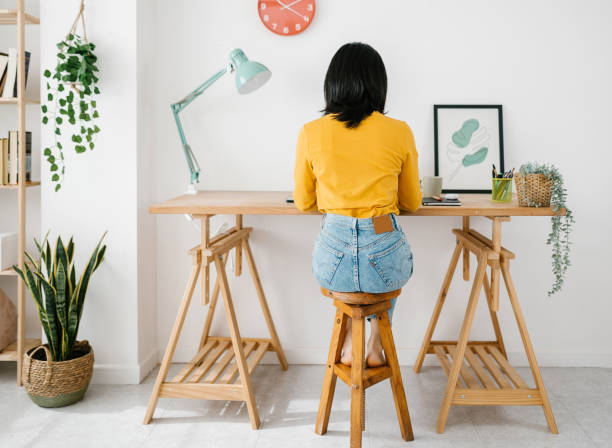istock Back view of young woman sitting on a workplace while working from home. 2172644654