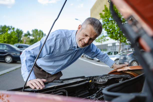 istock Man inspecting car engine on a sunny day in parking lot 2172648891