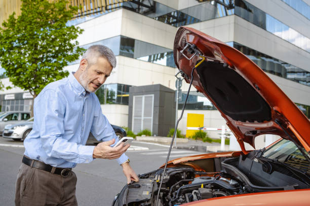 istock Mature man using smartphone beside broken down car on city street 2172649156