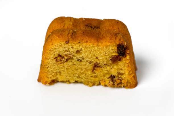 A high angle close up photograph of a partially sliced cinnamon coffee cake and a glass container with some cinnamon sticks.
