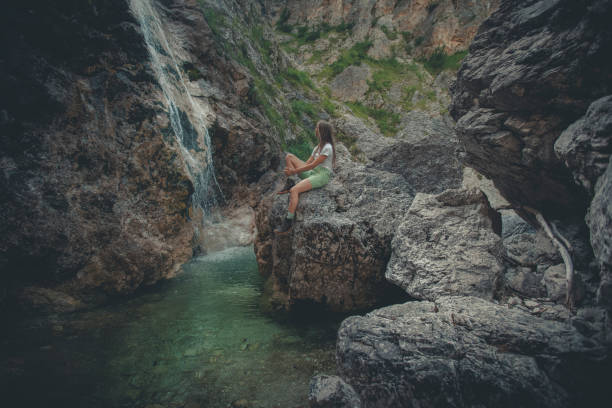 Carefree woman day dreaming while relaxing by the waterfall in nature.