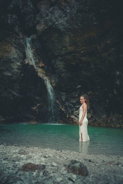 Young woman relaxes in pool below waterfall, Soca River