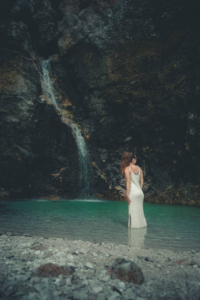 istock Young woman relaxes in pool below waterfall 2172668867