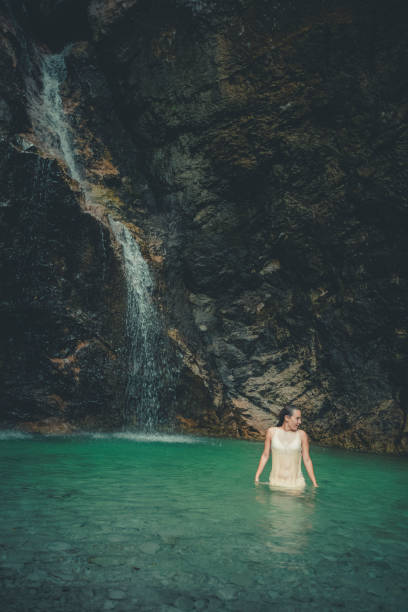 istock Young woman relaxes in pool below waterfall 2172669002