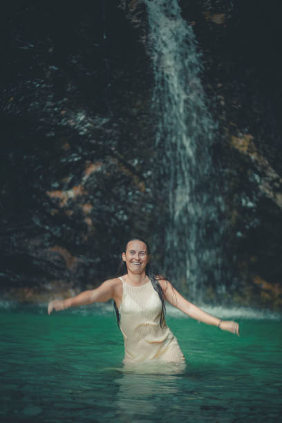 Young woman relaxes in pool below waterfall, Soca River