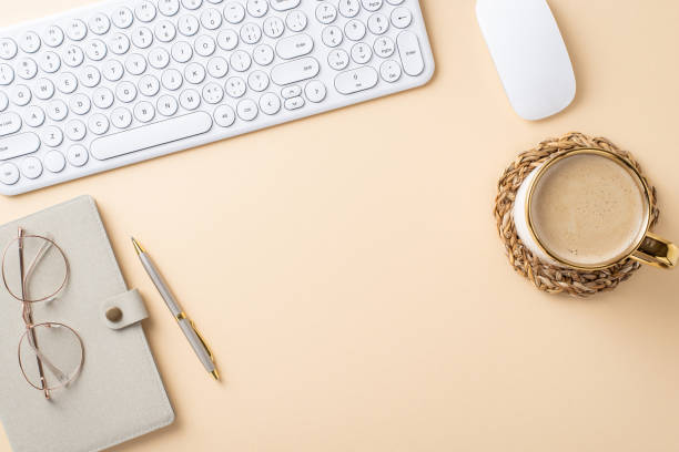 istock Top view of a stylish minimalist workspace featuring a keyboard, mouse, notebook, pen, glasses, and a cup of coffee on a pastel background 2172678276