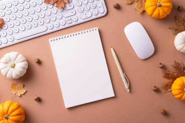 istock Flat lay of an autumn themed workspace featuring a keyboard, mouse, notepad, pen, and mini pumpkins to evoke creativity and seasonal warmth 2172678294
