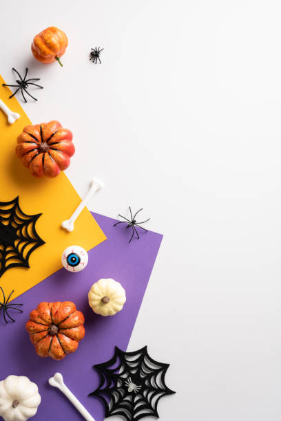 istock Creative vertical Halloween decorations featuring pumpkins, spider webs, and spooky elements on vibrant yellow and purple paper 2172678330